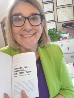 Barbara Baron holding a copy of her book "Called to Lead" open to the chapter she wrote