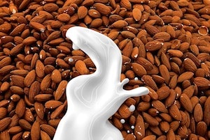 Pile of almonds with a splash of milk to depict non-dairy milk alternatives