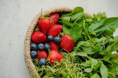 Strawberries, blueberries and leafy greens in a basket