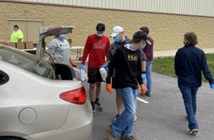 Food bank workers load items into a car