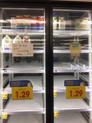 Shelves at grocery store with low supply of milk